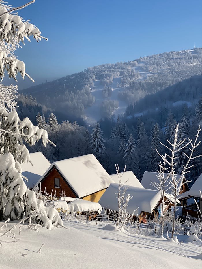 Idyllic winter scene with snow-covered chalets and mountains on a sunny day.