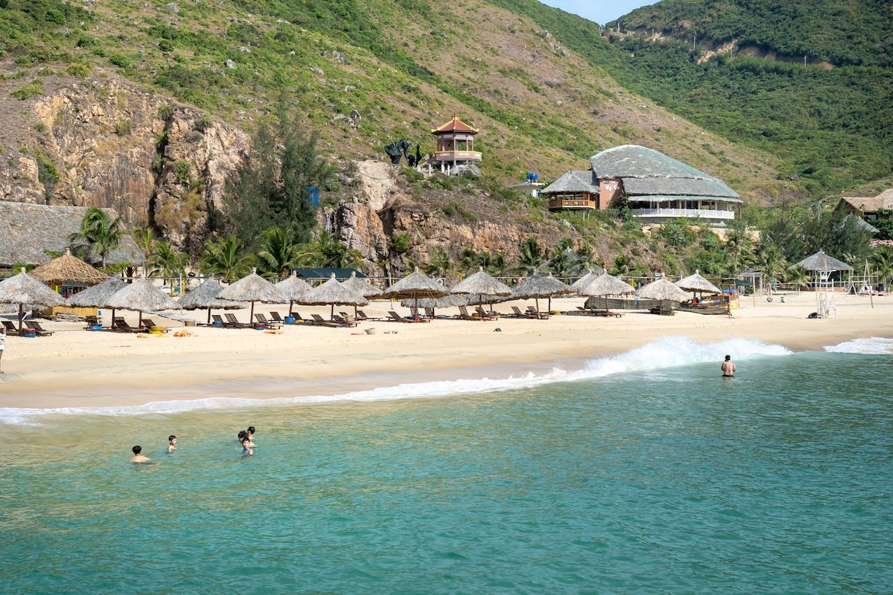 services-03 Tranquil beach scene featuring umbrellas, turquoise waters, and mountain views, perfect for relaxation.